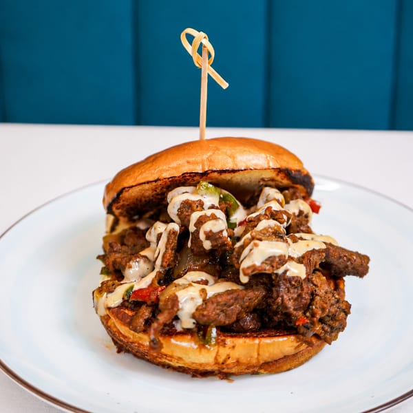 A large, juicy cheesesteak sandwich with melted cheese and peppers on a toasted bun.