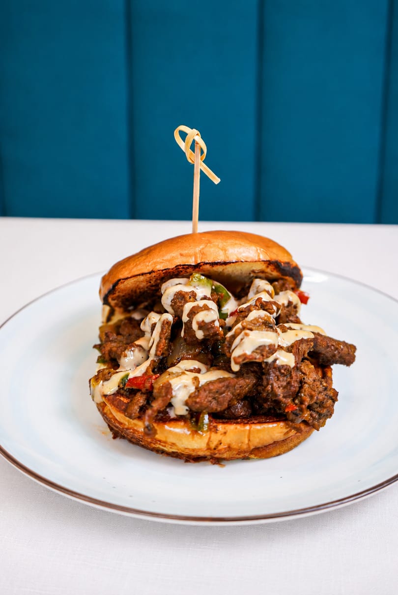 A large, juicy cheesesteak sandwich with melted cheese and peppers on a toasted bun.