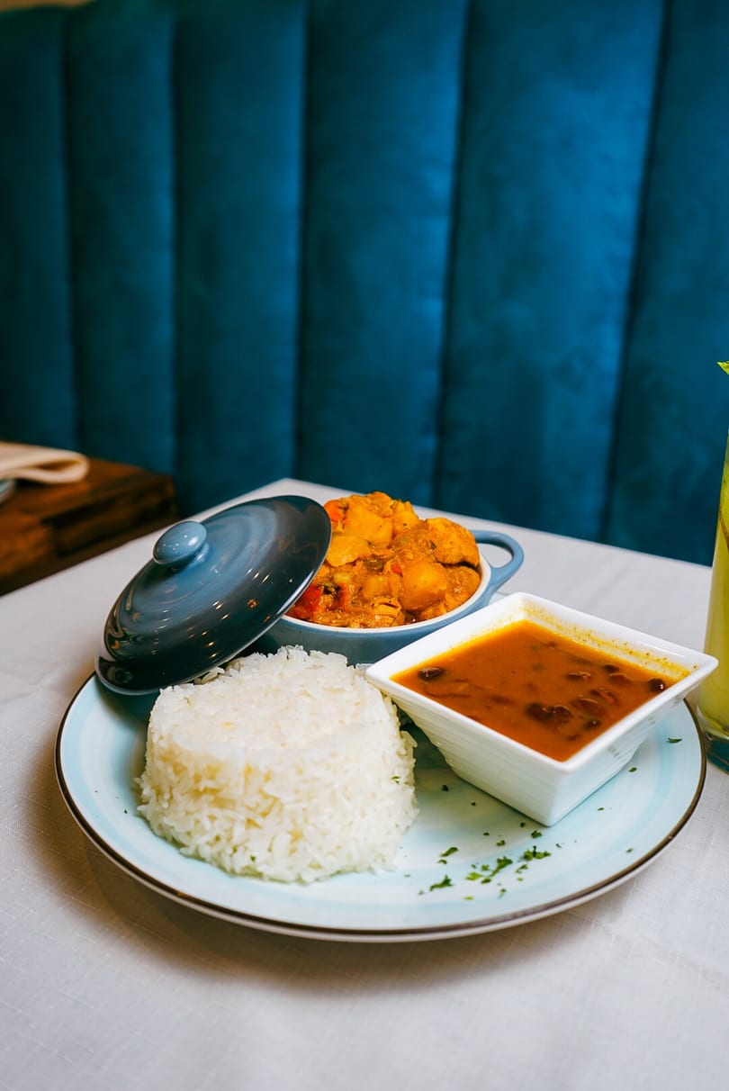 A plate of white rice, a bowl of red bean stew, and a pot of chicken curry.
