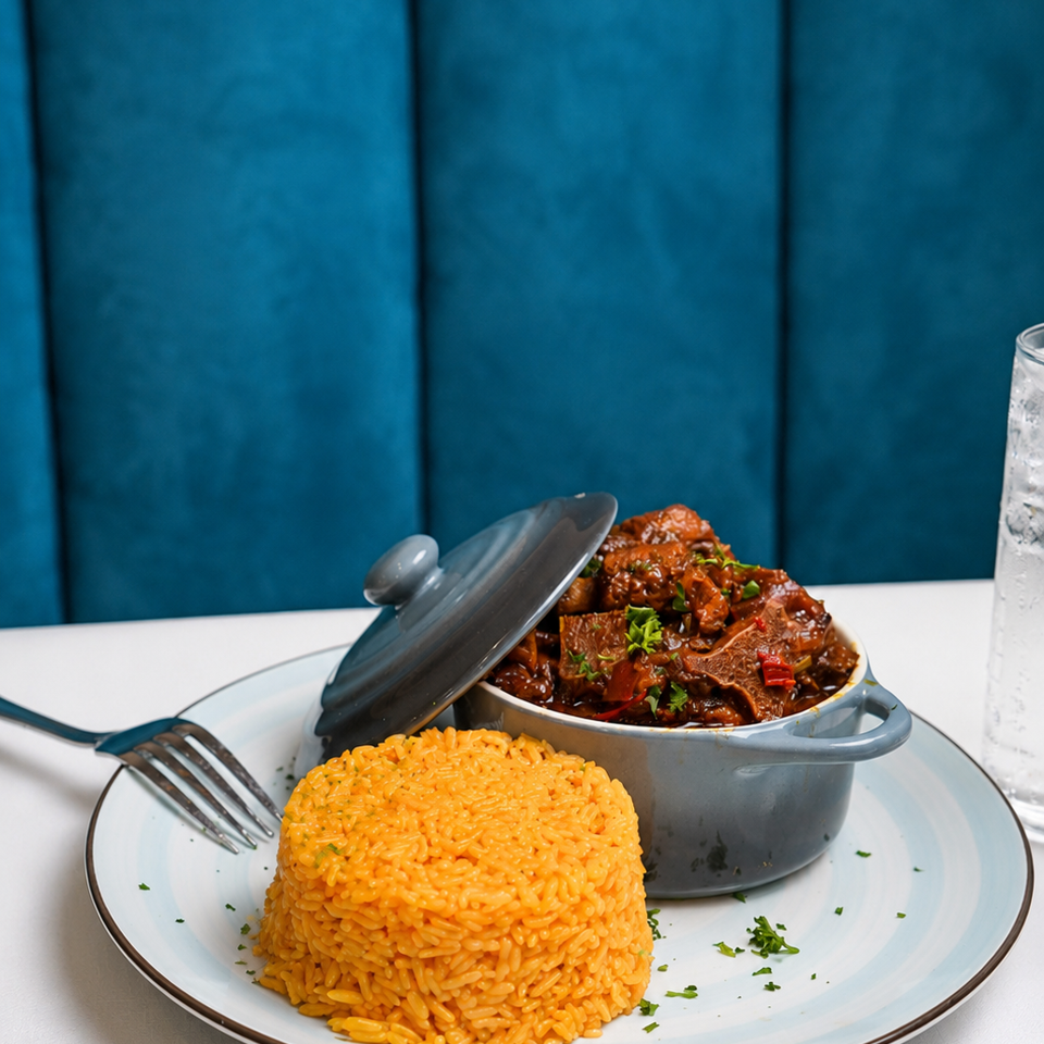 A gray pot of stewed meat and a mound of orange rice on a white and blue plate.